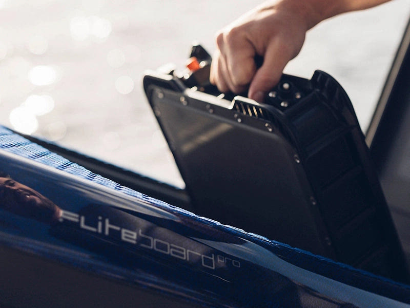 Rider sliding a battery into a Fliteboard